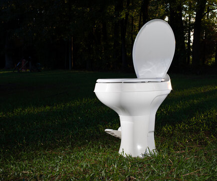 THis RV throne know as a plastic foilet has been thrown onto a field