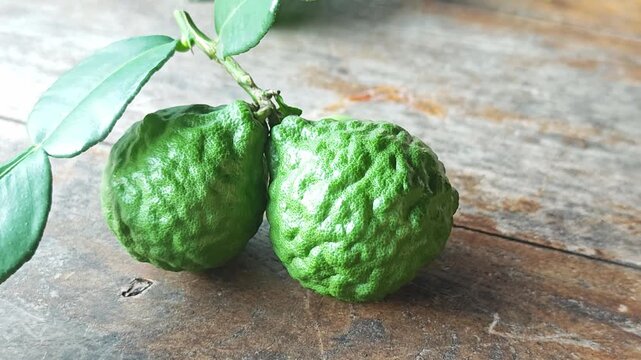 A pair of fresh green kaffir lime fruits on wooden table.