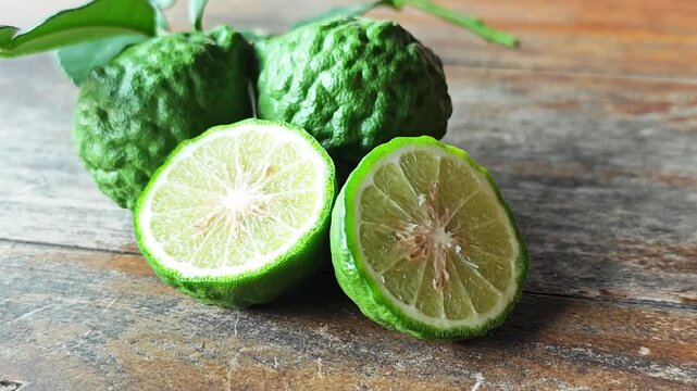 Fresh kaffir lime cut in half on wooden background.