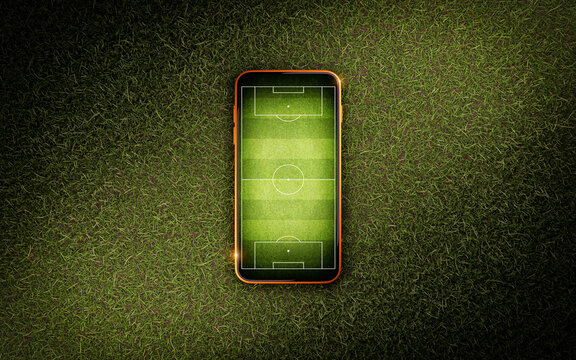 Mobile phone with soccer field screen on green grass lawn, top view