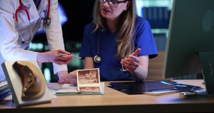 Female doctors examine patient breast ultrasound images in clinic. Women physicians conduct cancer diagnostics talking in medical office
