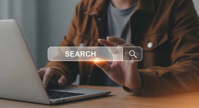 Person interacting with a digital search bar on a laptop computer