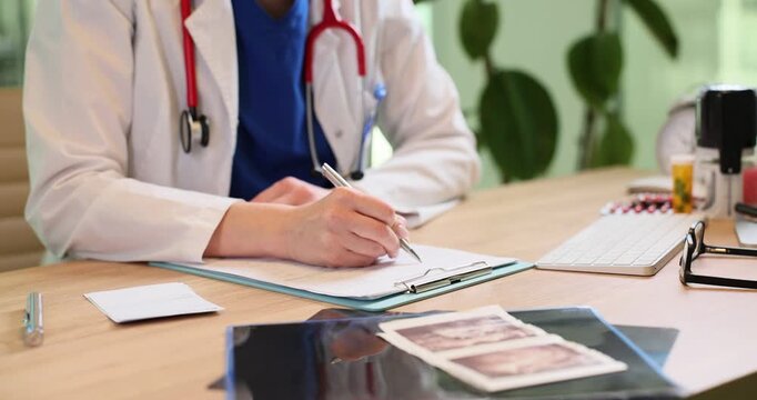 Female medic in robe writes medical records on clipboard in clinic. Woman doctor with stethoscope fills legal forms of patient treatment in hospital