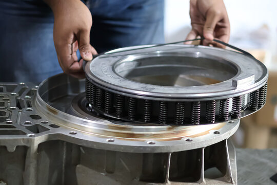A close-up shot of an industrial mechanic's hands installing a black rubber o-ring seal onto a heavy metal bearing housing assembly during a repair process.