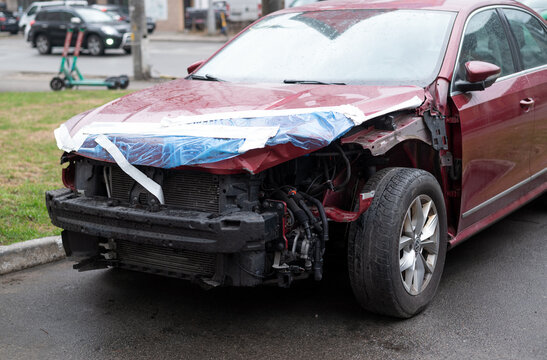 Kyiv, Ukraine. April 3, 2026. Damaged red Volkswagen car sedan with missing front bumper after car crash accident, parked on a city street.