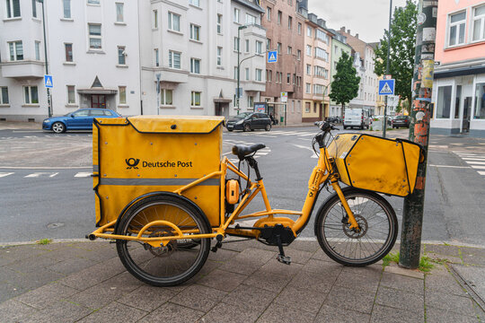 Dusseldorf, Germany - May 15 2026: Yellow branded Deutsche Post cargo bicycle stands parked at a city intersection on a quiet day