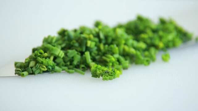 Close-up of a finely chop fresh green chives on a clean white cutting board