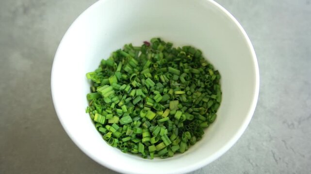 Close-up of a finely chop fresh green chives on a clean white cutting board