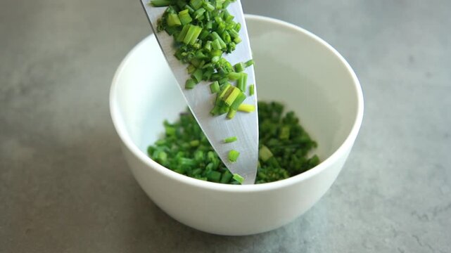 Close-up of a finely chop fresh green chives on a clean white cutting board