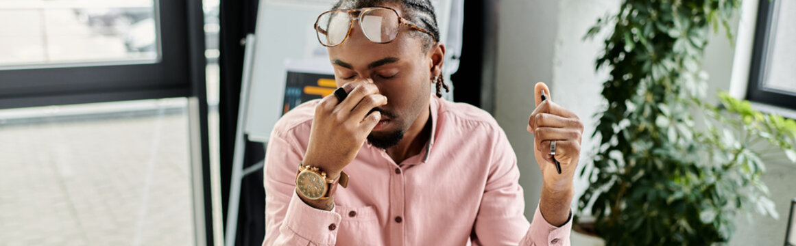 Young man experiencing tiredness while working as a manager in a modern space