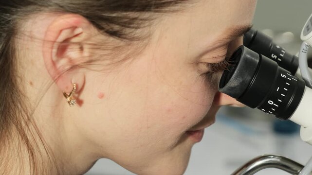 Specialist uses microscope for Pap test review. Gynecologist tracks sample details performing careful diagnostic observation in close view