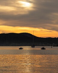 Sailboat and small boats anchored in a calm bay at sunset with orange sky, Mallorca, Spain © Ricardo