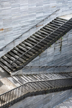 A diagonal stair crosses the stone facade, using railings, shadow, texture, and exterior geometry to make urban architecture read as a graphic surface