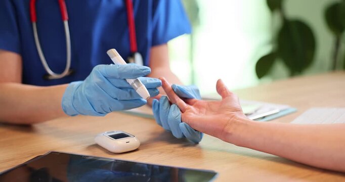Doctor in gloves uses glucometer to check patient sugar level in blood at appointment. Physician examines woman with diabetes disease in hospital