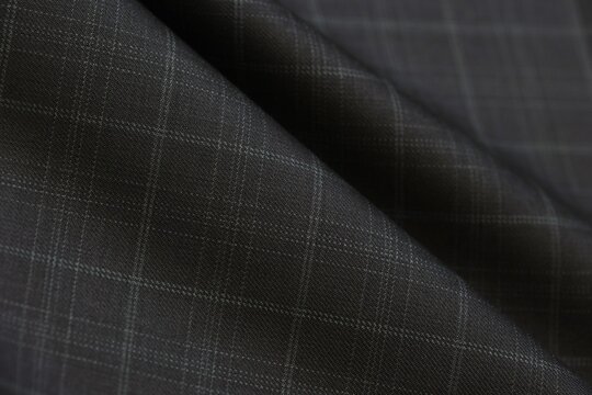 Grid check pattern defines this elegant charcoal black cashmere suiting fabric, perfect for luxury menswear fashion, tailoring textile backgrounds, and high-end bespoke apparel design texture.
