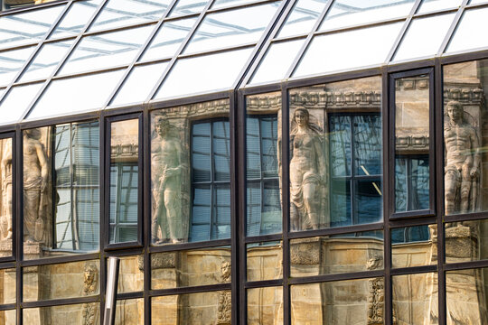 Under the glass roof, windows and facade details hold reflection from an urban building around the atrium, where heritage stone meets a modern grid