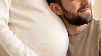 Fototapeta premium Man gently resting his head on pregnant woman's belly in a warm intimate moment