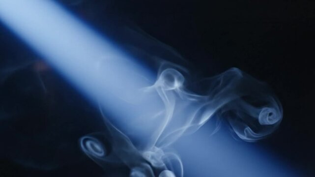 Abstract atmospheric smoke gracefully swirling and illuminated by a bright diagonal light beam against a dark background.