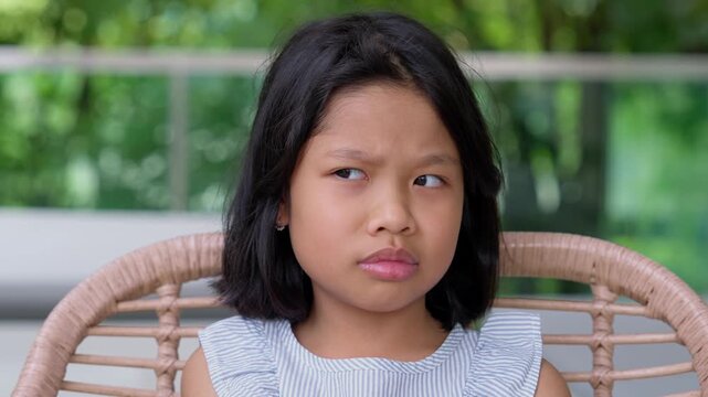 Curious Gaze: A young girl gazes intently, her eyes full of curiosity and a hint of skepticism. The backdrop of green foliage hints at an outdoor setting.
