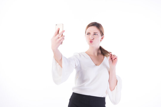 Playful businesswoman taking selfie with smartphone on white background