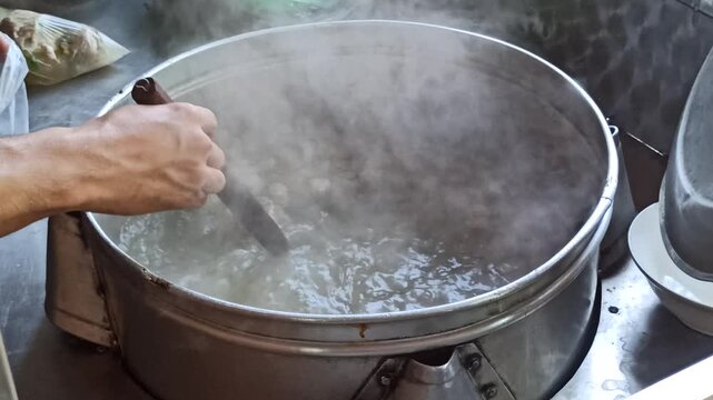 Large cooking pot filled with steaming meatball soup and assorted meatballs, showcasing authentic Indonesian culinary tradition.