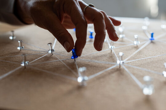 Hand placing a blue pin on a connected network model, close-up