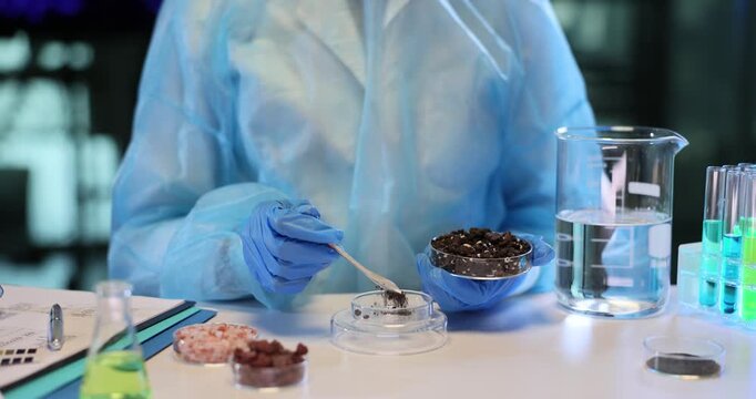 Lab assistant carefully transfers dry brown soil into transparent container. Experienced laboratory technician prepares sample for scientific analysis