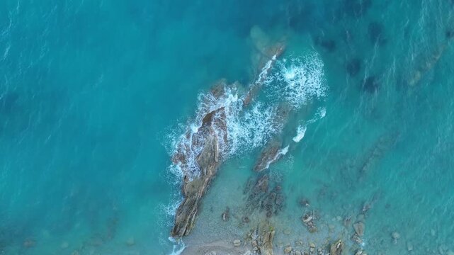 Drone top down view of turquoise ocean waves crashing on rocks