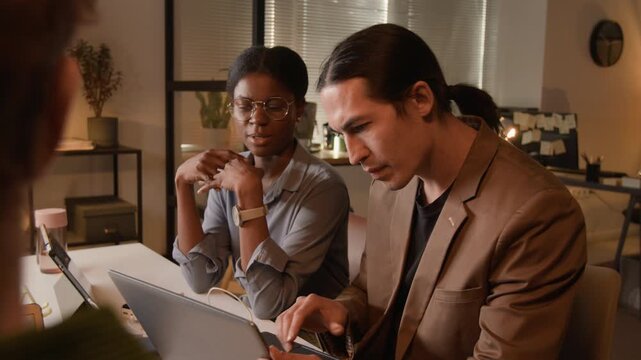 Multiethnic young developers, including Asian man and African American woman, discussing code and typing on laptop. Footage for corporate tech training and software commercials