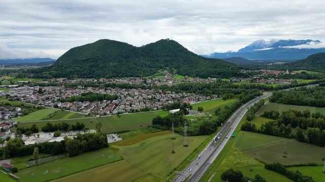 A scenic aerial drone view looking over the Brod district in Ljubljana, Slovenia, with the prominent double-peaked Smarna Gora hill rising in the mid-ground. Patchwork allotment gardens and fields