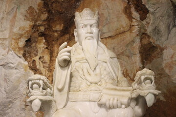Obraz premium Historical marble sculpture of seated elder with scroll inside limestone cavern.