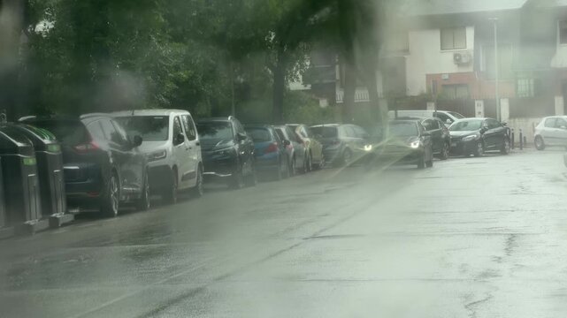 Cars driving through heavy rain on urban street