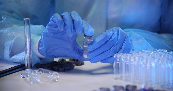 Laboratory worker closes lid of transparent bottle filled with experimental liquid. Lab technician intensely shakes container in sterile laboratory