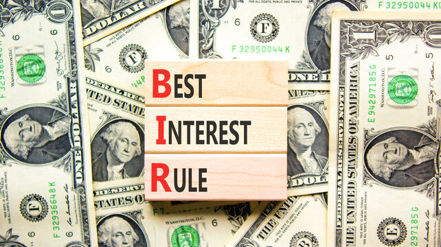BIR best interest rule symbol. Concept words BIR best interest rule on beautiful wooden blocks. Beautiful dollar bills background. Dollar bills. Business BIR best interest rule concept. Copy space.
