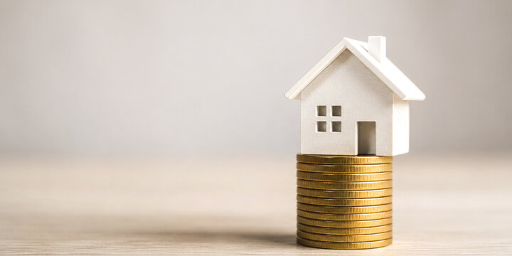 Real estate investment featuring a house model resting on a stack of coins