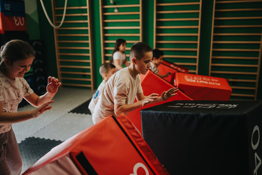 A group of children run and climb through foam obstacles in an indoor gym. Kids practice balance and coordination on a soft obstacle course during playtime.