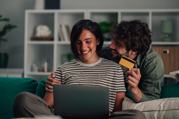 Happy couple shopping online with laptop and credit card, enjoying secure e commerce and digital...