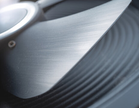 A steel blade skims a black spiral, like a quiet prophecy etched in motion