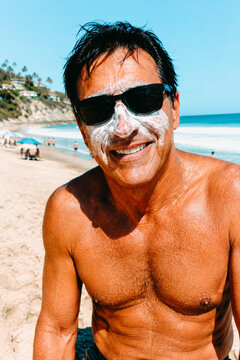 a man wears sunscreen on a beach