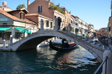Beautiful scenic view of a traditional gondola sailing under the Tolentini bridge in Venice, Italy. © Pro