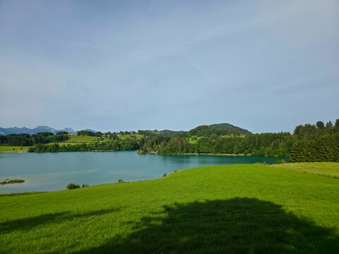 germany, radiant summer panorama of illasbergsee with lush green meadow foreground and tranquil forested lakeside scenery