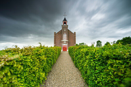 Storm clouds gather over the path leading to the quiet church.