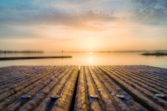 Golden sunbeams kiss the tranquil water from a weathered dock.