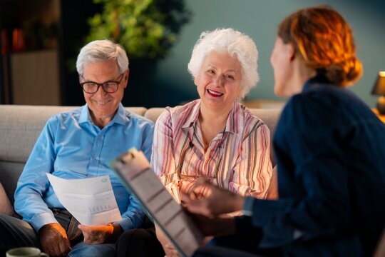 Professional advisor discussing Medicare options and healthcare benefits with senior couple at home.