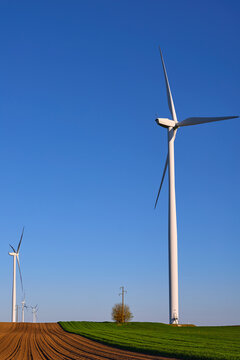 Wind turbines at sunset in green field &ndash; renewable energy, clean power, sustainable future.