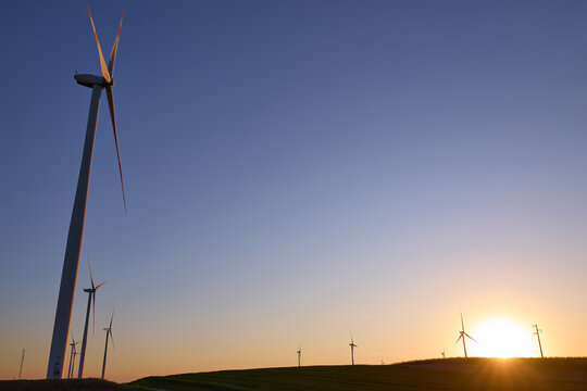 Wind turbines at sunset in green field &ndash; renewable energy, clean power, sustainable future.