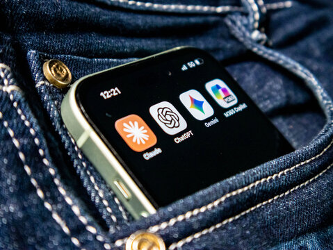 Smartphone inside a denim jeans pocket displaying popular artificial intelligence mobile applications including claude, chatgpt, gemini, and microsoft 365 copilot icons