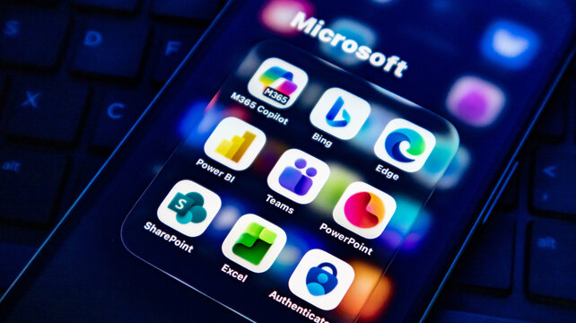 Closeup of a smartphone screen displaying various microsoft application icons including m365 copilot, bing, edge, teams, and powerpoint