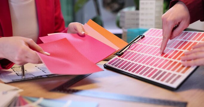 Women interior designers discuss material colors in company office. Female expert consults customer during decor shades choosing slow motion