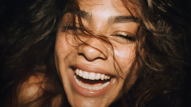 Radiant Smile: A close-up portrait of a young woman with wind-blown hair, her eyes closed and mouth open in a joyous, infectious laugh, embodying pure happiness and freedom.